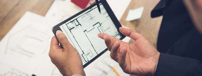 Real estate agent with client or architect team discussing a housing model and its blueprints digitally using a tablet computer