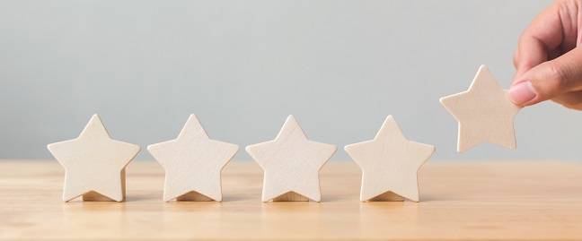 Hand putting wooden five star shape on table. 