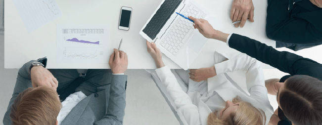 Team of people looking over data sheet and laptop