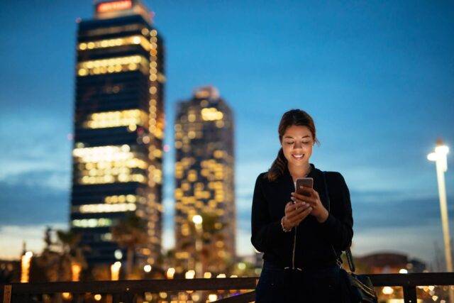 person on phone in front of high rise buildings