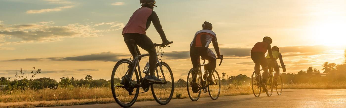 3 cyclist heading towards a sunset