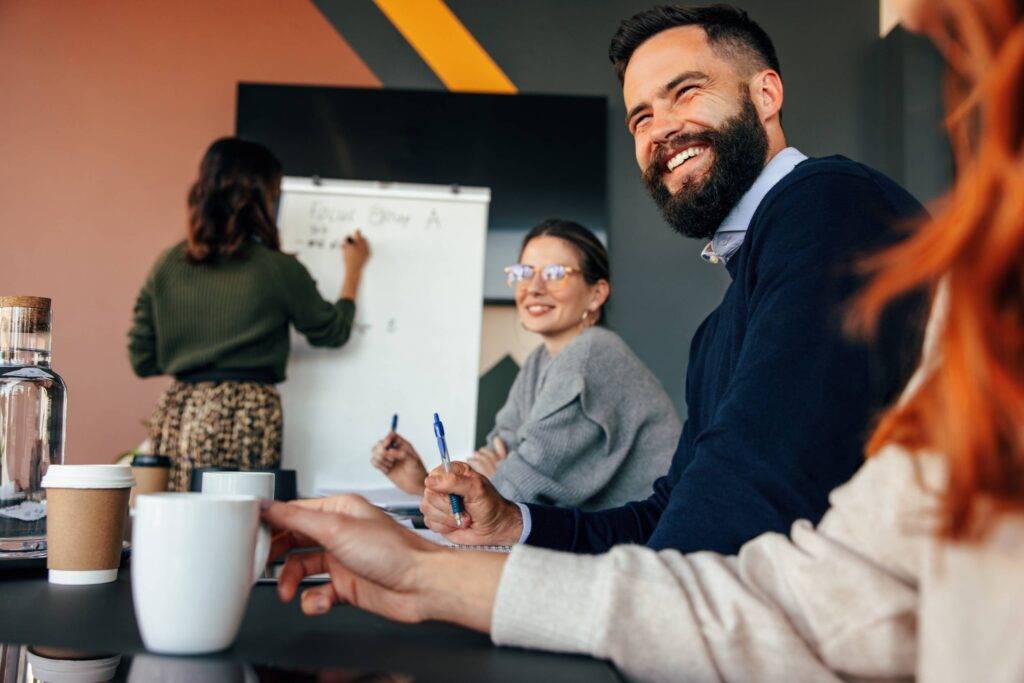 Happy businesspeople smiling during a boardroom meeting. Group of diverse businesspeople attending a presentation in a modern office. Young entrepreneurs working together as a team.