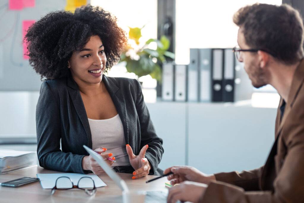 man and woman talking at a table in an office