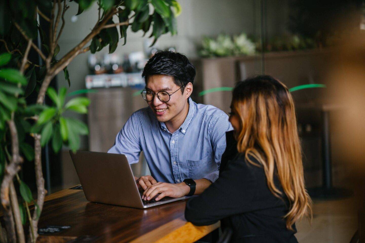 Two people discussing over a table with a laptop